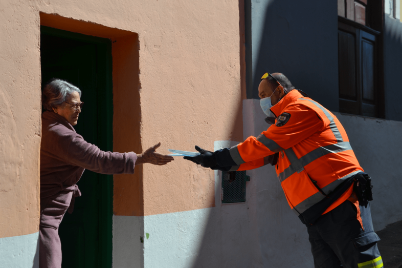 Un voluntario de Protección Civil entrega una mascarilla a una vecina de Valsequillo (Foto TA)